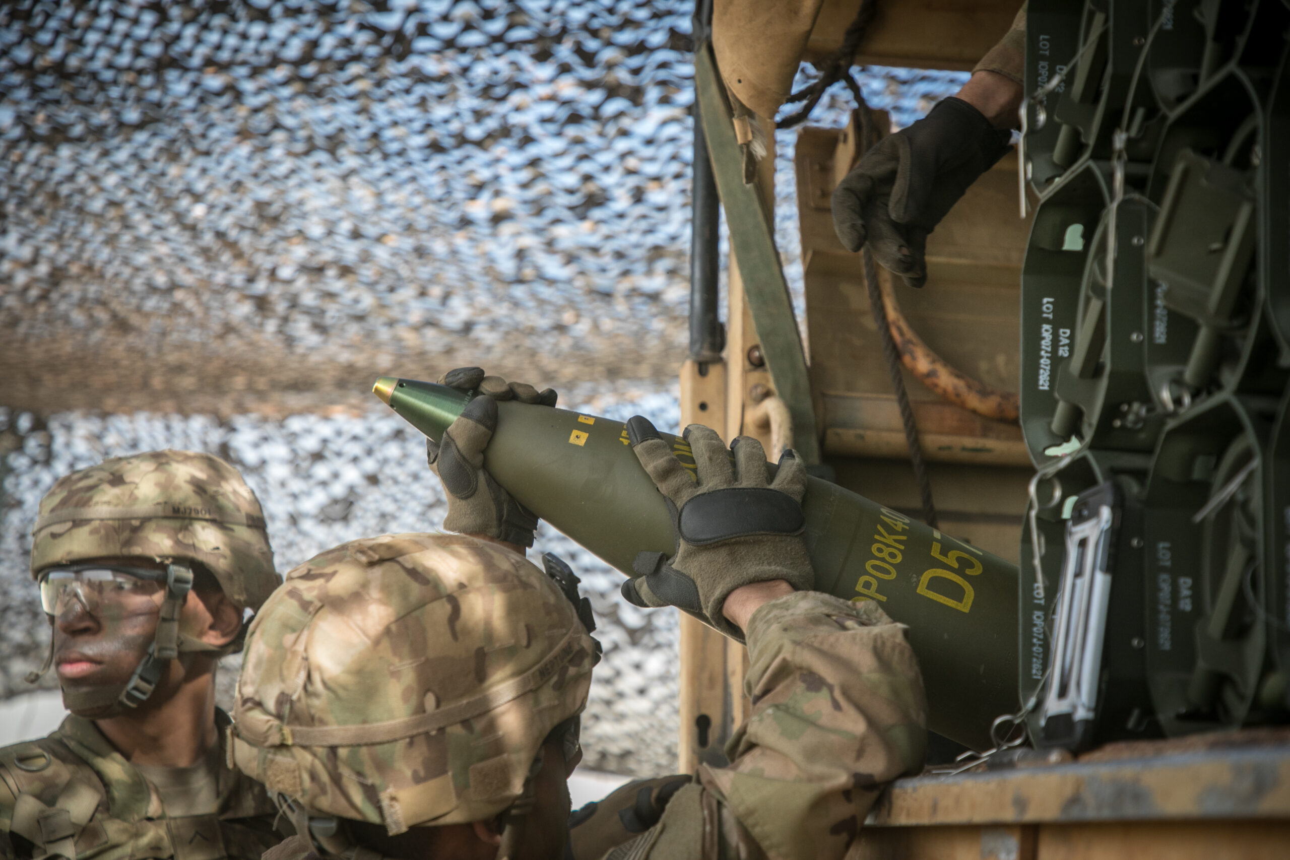 Soldiers handling a 155mm shell.